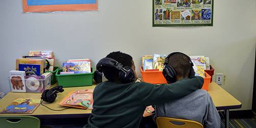 Adrian Malone, left, helps Gerald Elston adjust the volume on his headphones as the two listen to audiobooks at school in Washington, D.C. (Jahi Chikwendiu/The Washington Post via Getty Images)